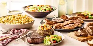 "Outback Steakhouse catering platters with grilled steak, chicken, ribs, pasta, and fresh salad options for group dining and events"

